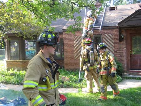 Firefighter practicing ventilation of roof on home scheduled for demolition