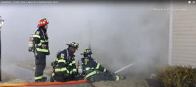 Prospect Heights firefighters operating a large hose stream at a extra-alarm townhouse fire in Buffalo Grove